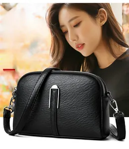 Close-up of litchi grain leather crossbody bag with silver metal ring buckle and strap