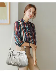 Detail showing the white pleated leather handbag with kangaroo logo and crossbody strap
