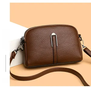 Close-up of brown litchi pattern leather texture and silver metal buckle on a shoulder bag