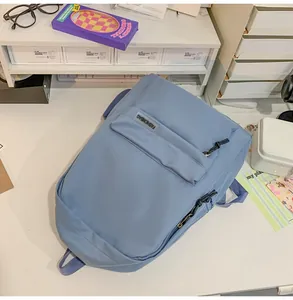 Gedetailleerde weergave van lichtblauwe minimalistische rugzak op wit bureau met kantoorartikelen