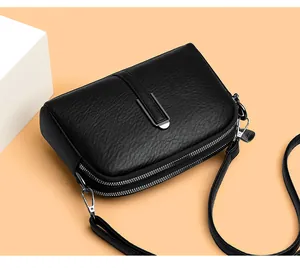 Detail view of black lychee leather crossbody bag with dual zippers and silver U-shaped buckle