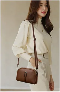 Detail of the dark brown lychee textured leather shell bag with metal zipper and strap