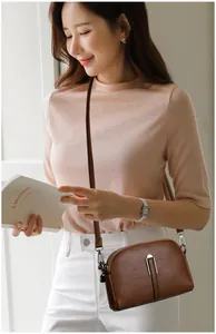 Detailed view of a brown textured leather shell crossbody bag worn by a model