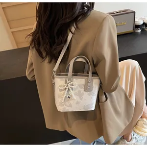 Detail of a beige bucket bag with butterfly prints and decorative pearl bow charms