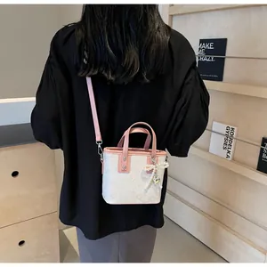 Detail of white bucket bag with pink trim, butterfly pattern and pearl bow pendant