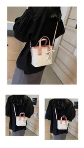 Detail showing white bucket bag with pink handles, butterfly print and pearl charm