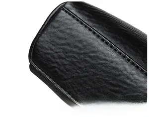 Close-up of black leather crossbody bag showing detailed grain and reinforced stitching