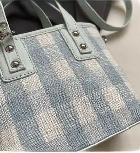 Close-up of blue and white checkered fabric detail with light blue leather and silver rivets
