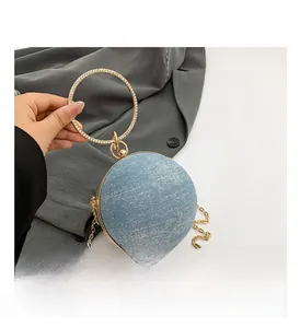 Close-up of blue spherical evening bag with denim texture, sequins, and rhinestone handle