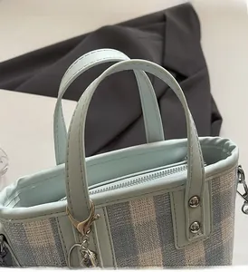 Detail of blue plaid fabric handbag showing comfortable handles and metal rivet hardware