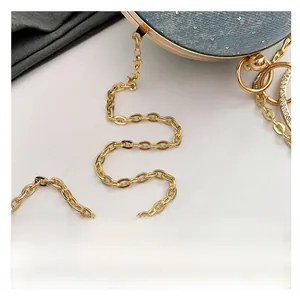 Detailed close-up of a golden chain strap on a blue rhinestone round evening clutch bag