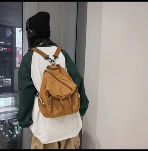 Detailed back view of a brown canvas backpack worn by a model in a modern urban interior