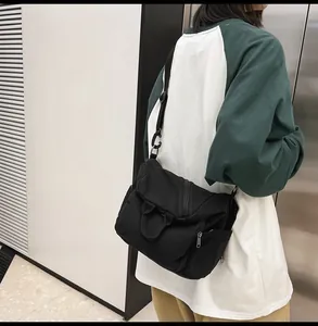 Close-up of black canvas messenger bag showing adjustable strap and side pockets on model