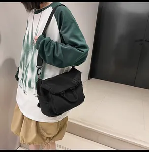 Side view of black washed canvas messenger bag with adjustable strap worn by model