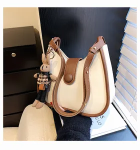 Detail van de crème hobo-tas met bruine bies, voorzien van een konijntje en metalen gesp