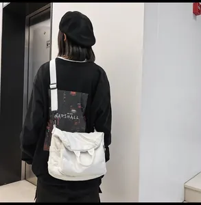 Detailed view of white canvas messenger bag featuring top handle and adjustable shoulder strap