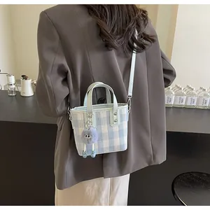 Detail of blue and white checkered mini tote bag with plush charm on a model's shoulder
