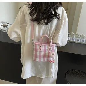 Detailed view of pink and white checkered crossbody bag with cute plush eyeball charm