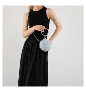 Detail of round light blue evening bag with gold ring handle and chain strap for women