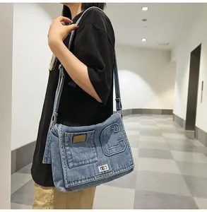 Detail of blue washed denim shoulder bag with embossed letter C and metal twist lock