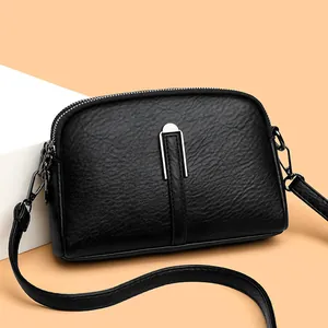 Minimalist black faux leather shell crossbody bag with silver U-shaped metal buckle detail