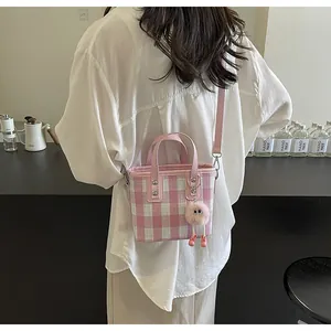 Detail of pink plaid mini bucket bag with a plush monster charm and leather handle