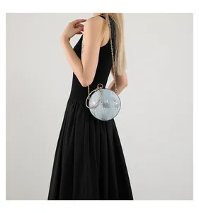 Detail of a spherical silver evening bag with blue sequins and a metal ring handle