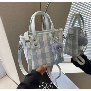 Detail of light blue plaid tweed bucket bag with soft leather handles and eye charm