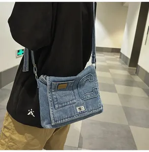 Detail of denim crossbody bag with C letter patch and metal turn-lock on the flap