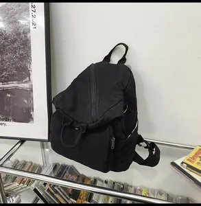 Detail of a black washed canvas backpack with front zipper pocket and side pockets