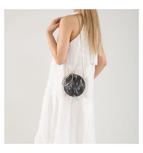 Detail of round black evening clutch with sparkling silver texture and gold ring handle