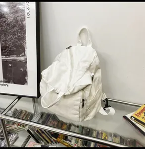 Detail view of white canvas backpack featuring durable dual-zipper and reinforced top handle
