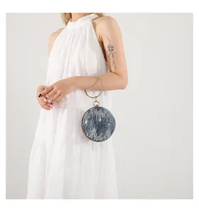Detail of round navy evening bag with geometric texture and gold metal ring handle