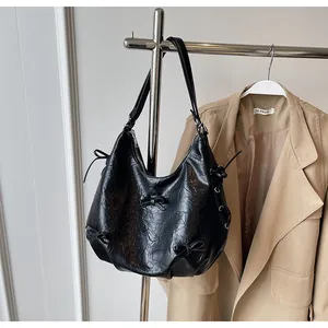 Detailed view of a black hobo bag with textured faux leather and bow ribbon accents