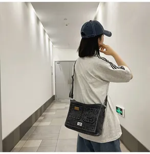 Detail of dark gray washed denim crossbody bag with adjustable strap on a female model