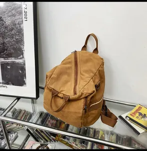 Detail of a brown canvas backpack showing zipper closure and durable metal D-ring buckle