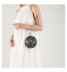 Detail of round evening bag with grey sequins, crystal ring handle on white dress