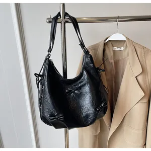 Detail of wrinkled black leather tote bag featuring chic bow accents and metal eyelets