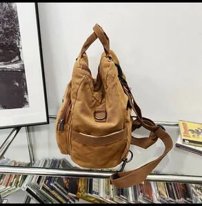 Detail view of brown canvas bag showing zipper compartments and adjustable strap texture