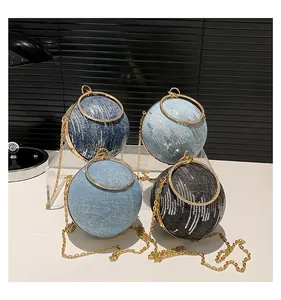 Detail of round denim clutch bags with sequins, gold hardware, and metal ring handles