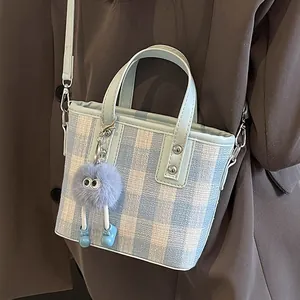 Blue and white plaid crossbody bucket bag with blue leather trim and plush pendant