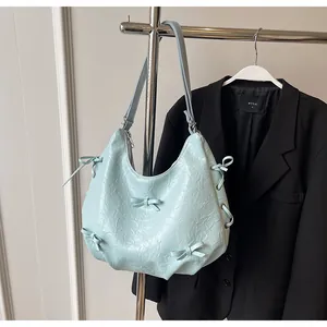 Detail of mint blue tote with bow decoration and drawstring on wrinkled fabric texture