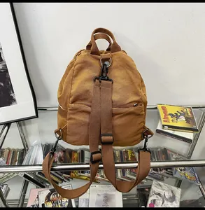 Detailed back view of dark brown canvas backpack with adjustable straps and zipper