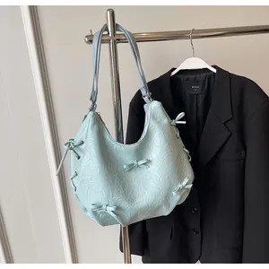Detail of light blue wrinkled texture shoulder bag with decorative bows and side drawstrings