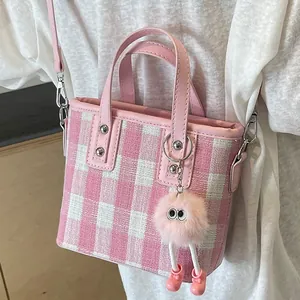 Pink and white gingham tote bag with plush charm shown on model in a soft lighting