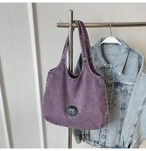 Detail of purple washed denim tote bag with butterfly patch and wide shoulder strap