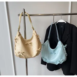 Detail of pleated shoulder bags with bow accents in beige and light blue colors
