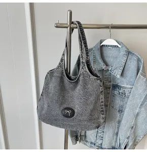 Detailed macro view of denim tote texture with silver bow and black logo patch decor
