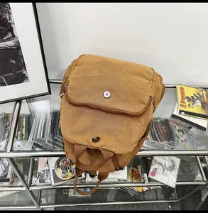 Close-up of vintage brown canvas backpack featuring metal magnetic buckles and zipper details