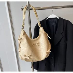 Detail of cream hobo bag with wrinkled leather texture and cute ribbon decorations